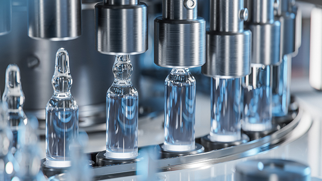 Línea de producción automatizada en una fábrica farmacéutica, con varias ampollas médicas alineadas mientras son llenadas y selladas por maquinaria industrial.