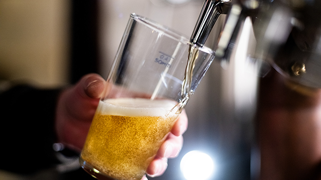 Bartender pouring crafted beer from tap in glass